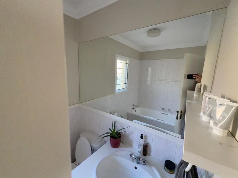 A functional bathroom featuring a built-in vanity with basin, a bathtub, and a large wall-mounted mirror.