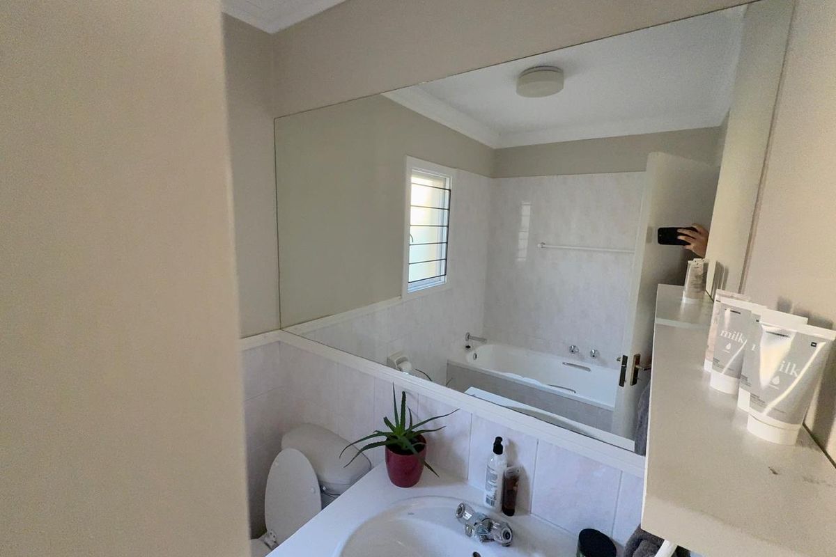 A functional bathroom featuring a built-in vanity with basin, a bathtub, and a large wall-mounted mirror.