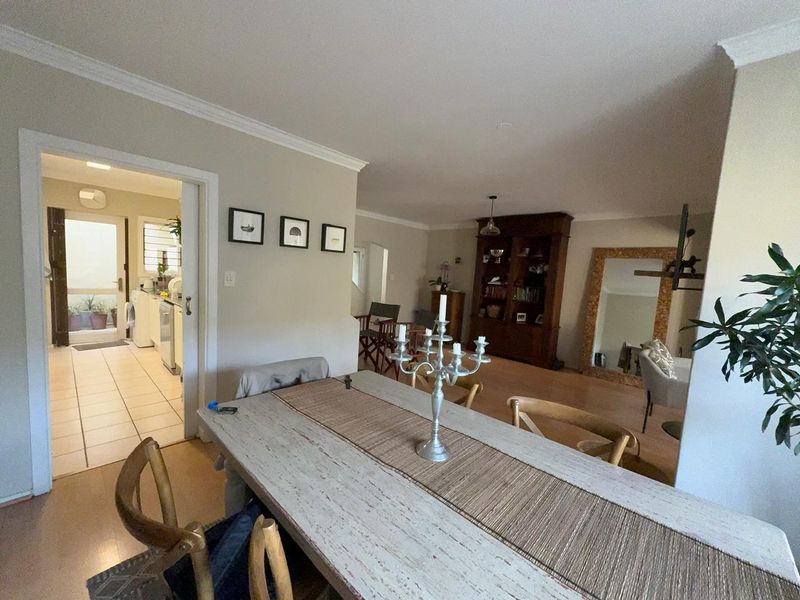 Open plan dining and living area featuring laminate flooring, cove cornicing, and direct access to a tiled kitchen space.
