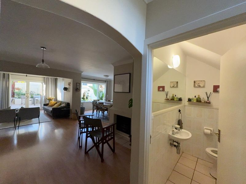 Open-plan living and dining area featuring a fireplace and sliding doors to the patio, adjacent to a compact guest bathroom with a wall-mounted basin.