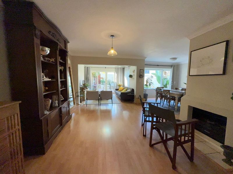 Spacious open-plan living and dining area featuring laminate flooring, a built-in fireplace, and sliding glass doors leading to the outdoor space.