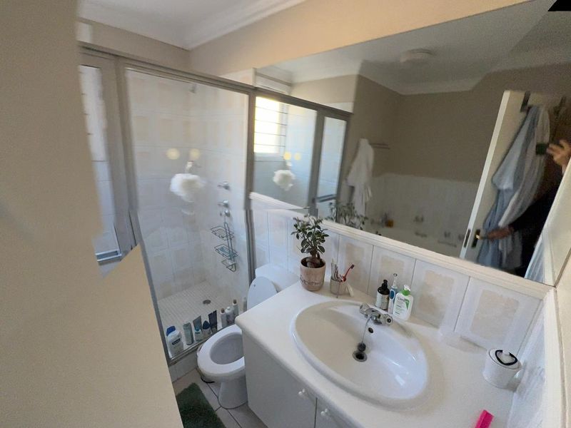 A functional bathroom featuring a shower enclosure, vanity cabinet with integrated sink, and a large wall-mounted mirror.