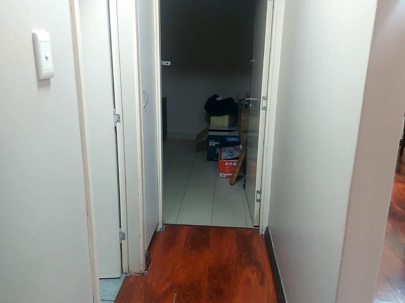 A functional hallway connecting living areas to a secondary room, featuring a transition between laminate and tiled flooring.