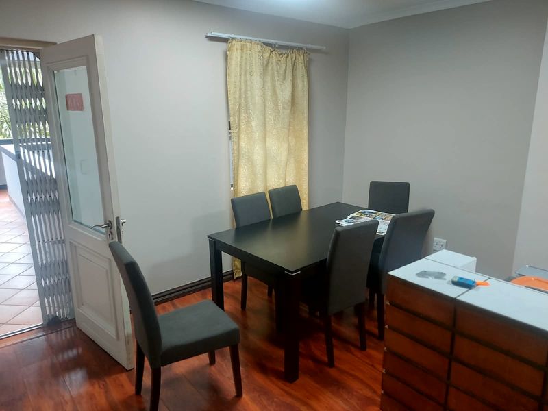 Dining area featuring laminate flooring and direct access to an outdoor balcony through a security gate.