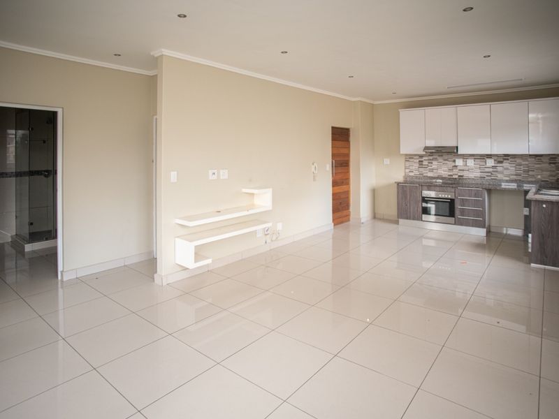 Spacious open-plan living area featuring tiled floors, recessed lighting, and a modern kitchen with granite countertops, built-in oven, and extractor fan.
