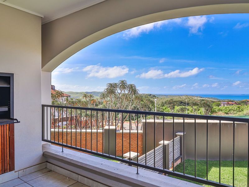 A covered balcony featuring a built-in braai, metal balustrade, and expansive views of the surrounding landscape and coastline.