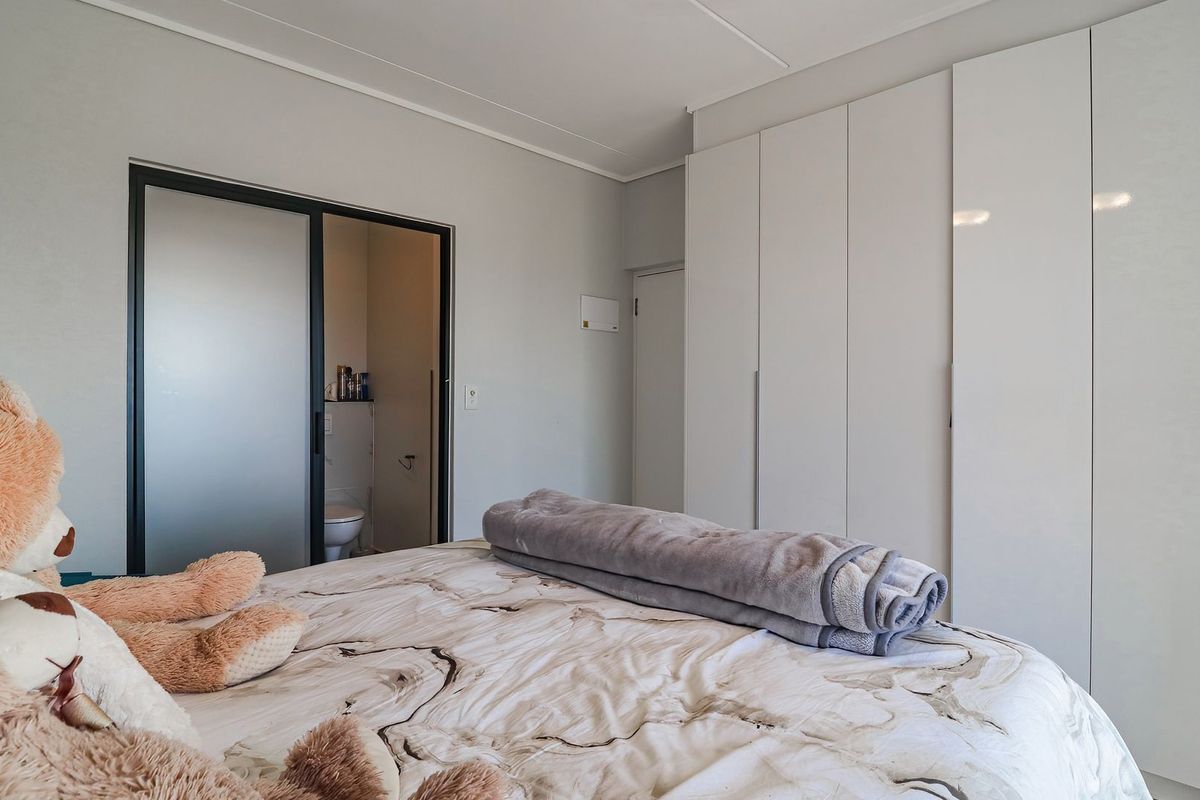 A well-maintained bedroom featuring extensive built-in cupboards and a sliding door providing access to an en-suite bathroom.
