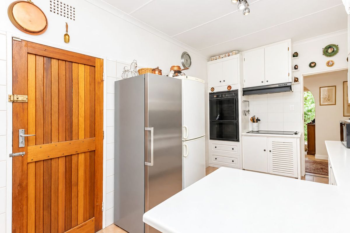 A functional kitchen featuring built-in oven, extractor fan, fitted cabinetry, and a solid timber door, offering a clean and practical workspace.