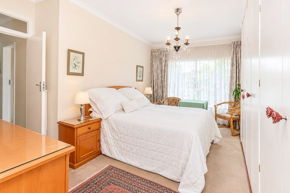 A well-maintained bedroom featuring built-in cupboards, a classic chandelier, and sliding glass doors that provide natural light.