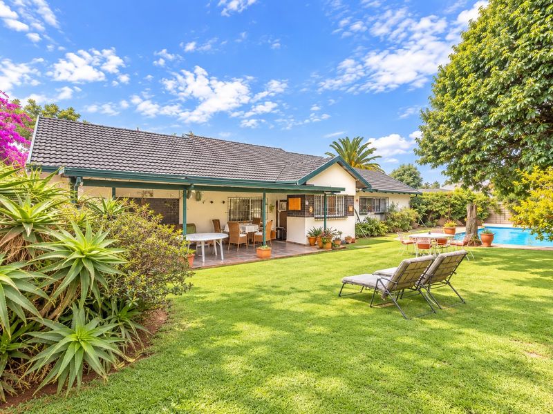 A spacious rear garden featuring a well-maintained lawn, a covered patio area, and a swimming pool, ideal for outdoor relaxation and entertainment.