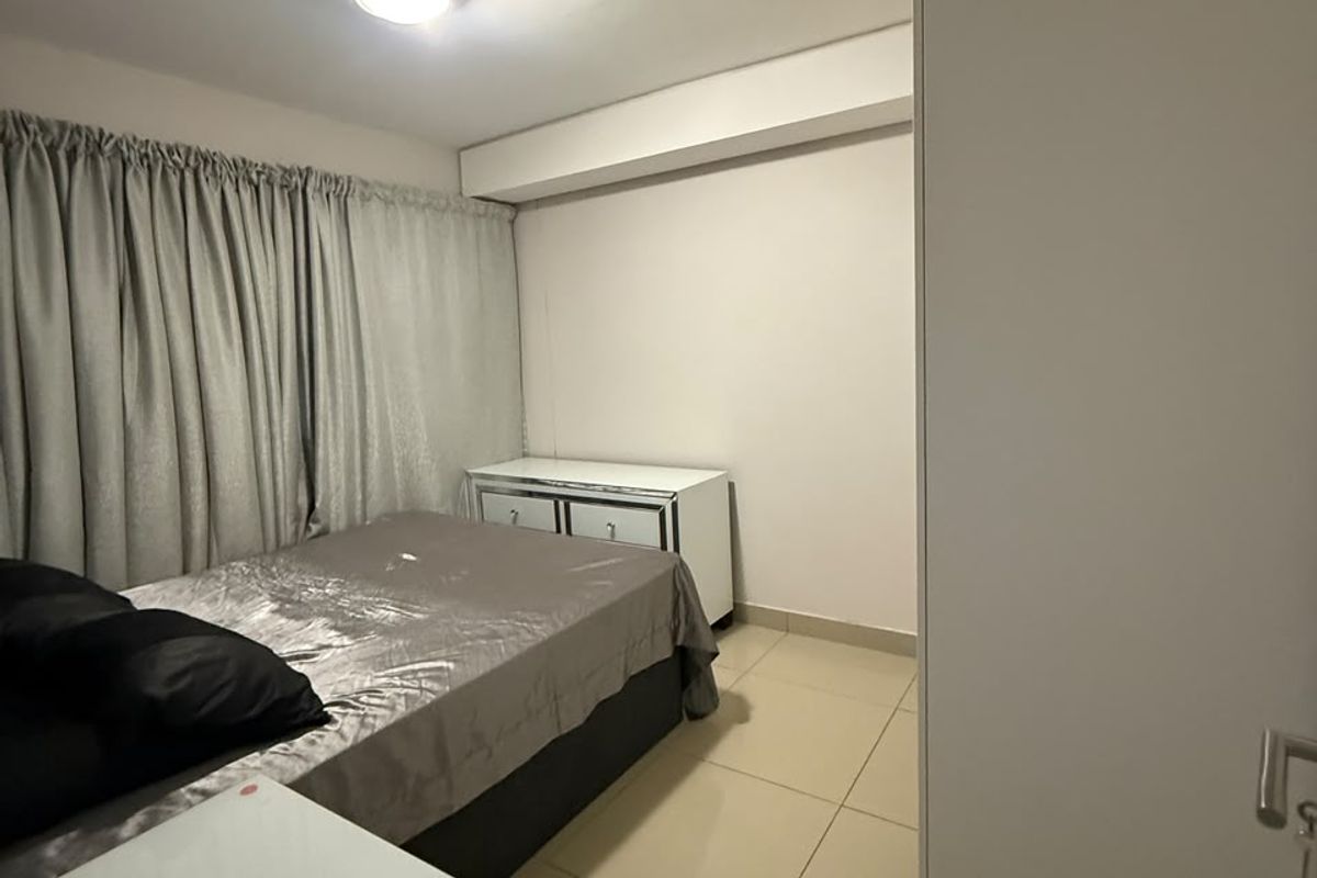 A functional bedroom featuring tiled flooring, a built-in wardrobe, and neutral wall finishes, providing a clean and simple living space.