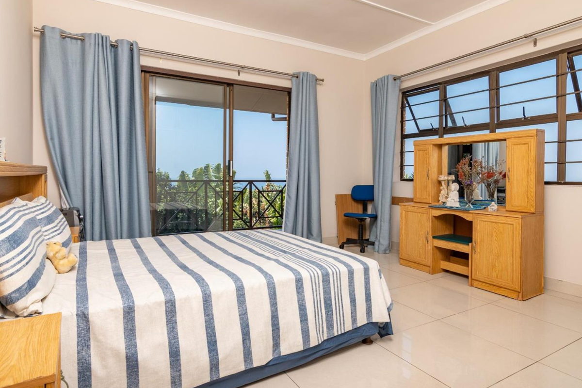 Spacious bedroom featuring tiled flooring, a built-in headboard, and a sliding glass door providing access to an outdoor balcony with scenic views.