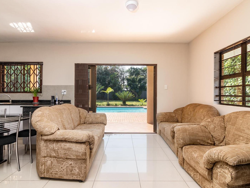 Open-plan living and kitchen area featuring tiled floors, granite countertops, and direct access to the outdoor patio and swimming pool area.