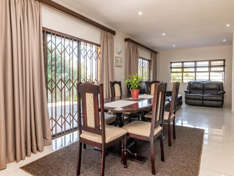 Spacious open-plan living and dining area featuring neutral tiled flooring, recessed lighting, and large sliding doors providing access to the outdoor space.