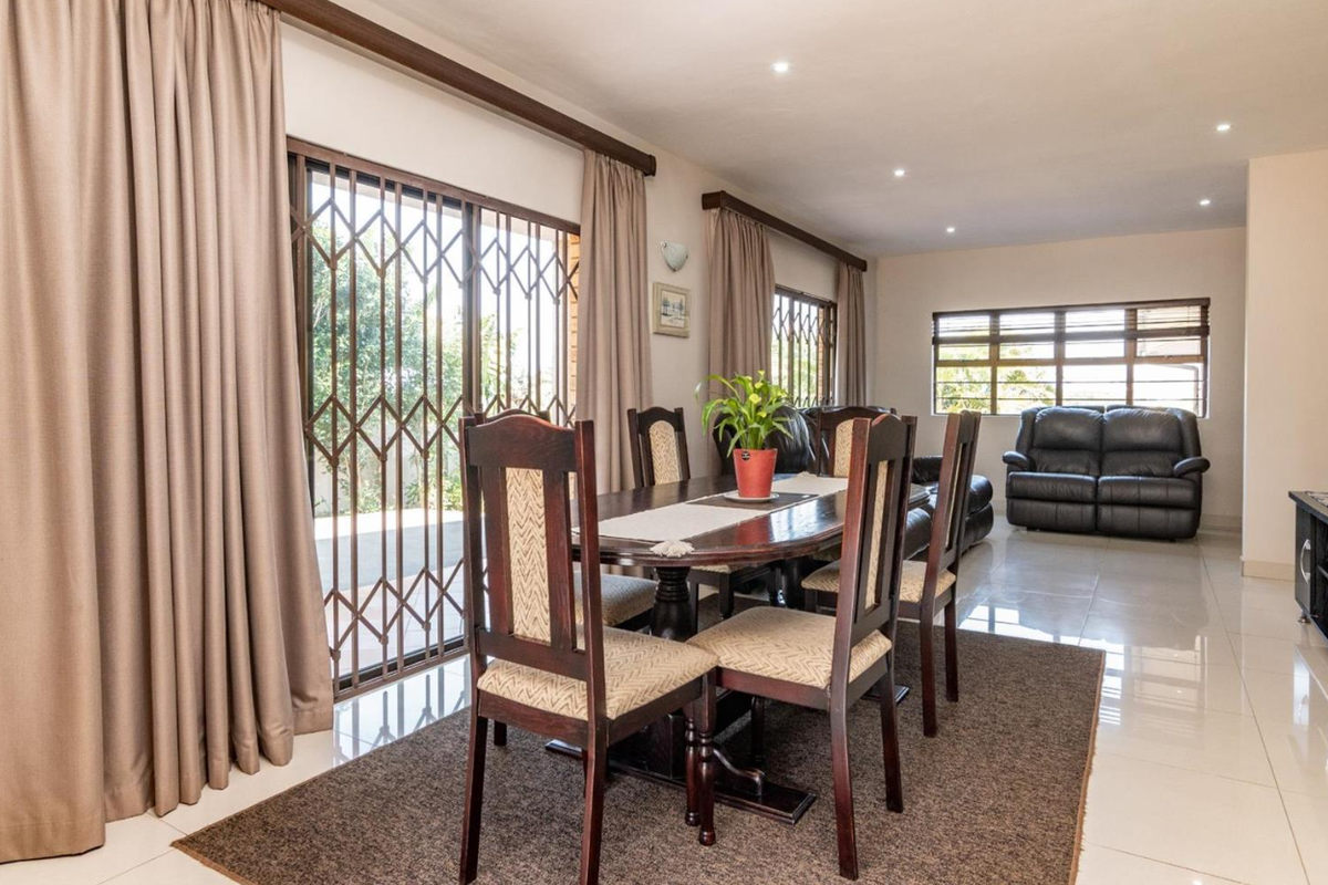 Spacious open-plan living and dining area featuring neutral tiled flooring, recessed lighting, and large sliding doors providing access to the outdoor space.