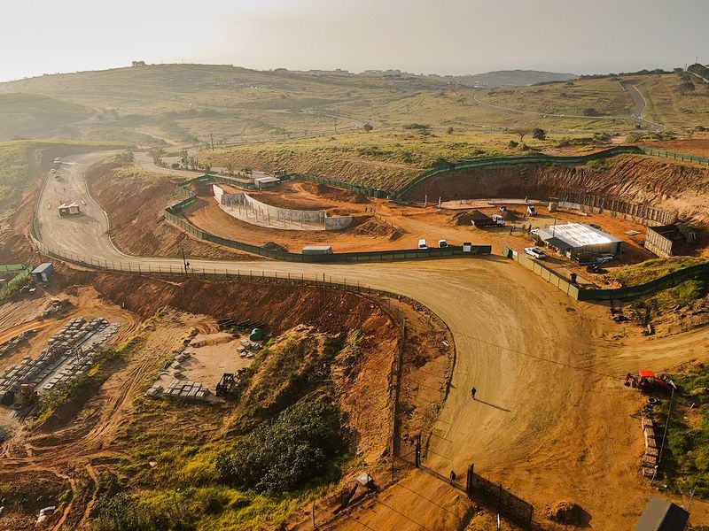 Aerial view of a residential development site showing ongoing earthworks, perimeter fencing, and internal road infrastructure.