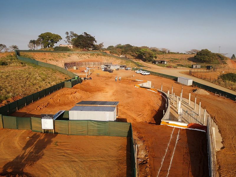Aerial view of a residential development site showing ongoing earthworks, retaining walls, and concrete structural columns in progress.