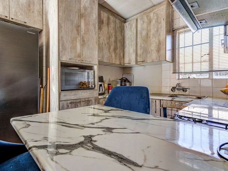 A functional kitchen featuring marble-look countertops, built-in cabinetry, and a tiled backsplash, offering a practical layout for daily meal preparation.