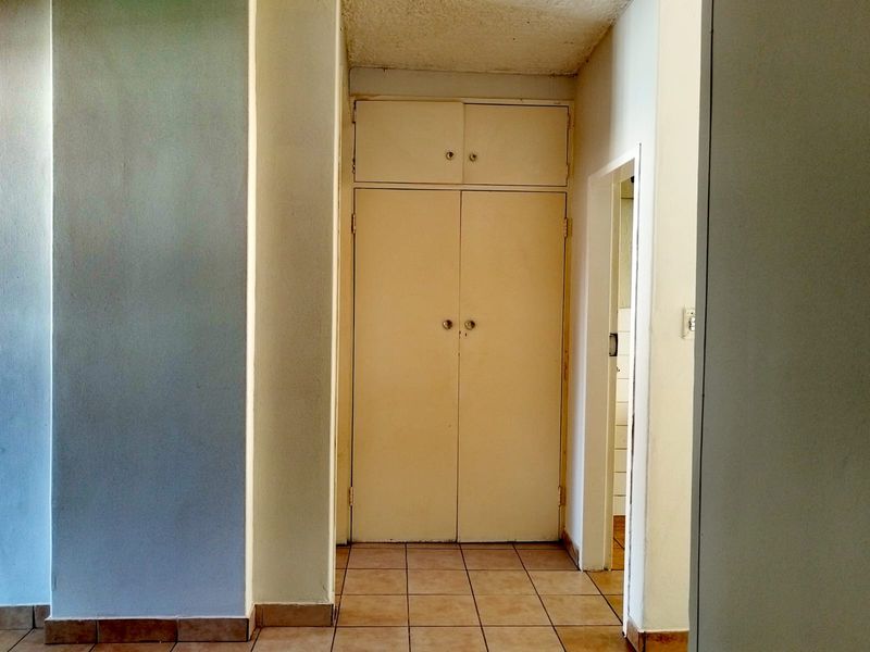 A functional hallway featuring built-in storage cupboards and tiled flooring, providing a clean transition space within the flat.