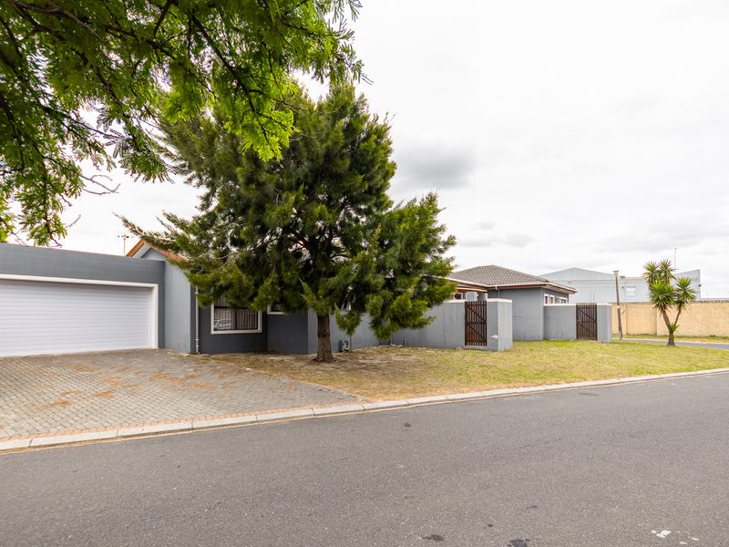 Front view of a residential property featuring a paved driveway, single garage, and enclosed boundary wall with gated access.