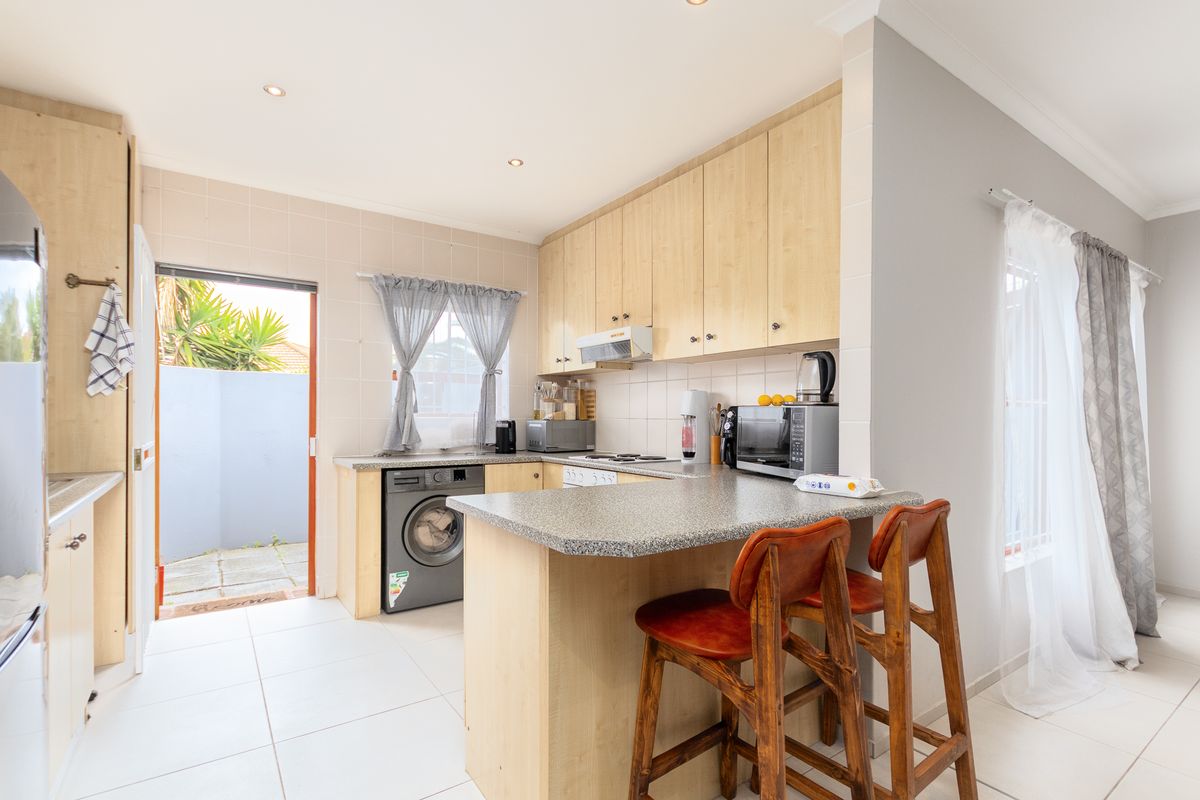 A functional kitchen featuring light wood cabinetry, granite countertops, a breakfast nook, and direct access to an outdoor area.