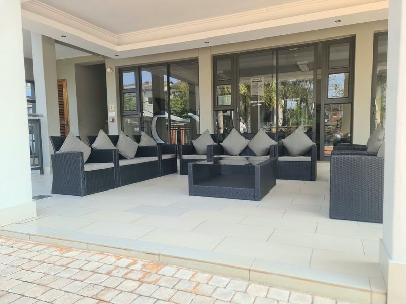A spacious covered patio featuring modern tiled flooring, recessed ceiling lighting, and large aluminium sliding doors providing seamless access to the interior living space.