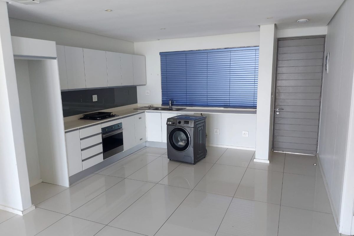 Modern kitchen featuring white cabinetry, integrated oven and hob, tiled flooring, and a neutral color palette, offering a clean and functional workspace.