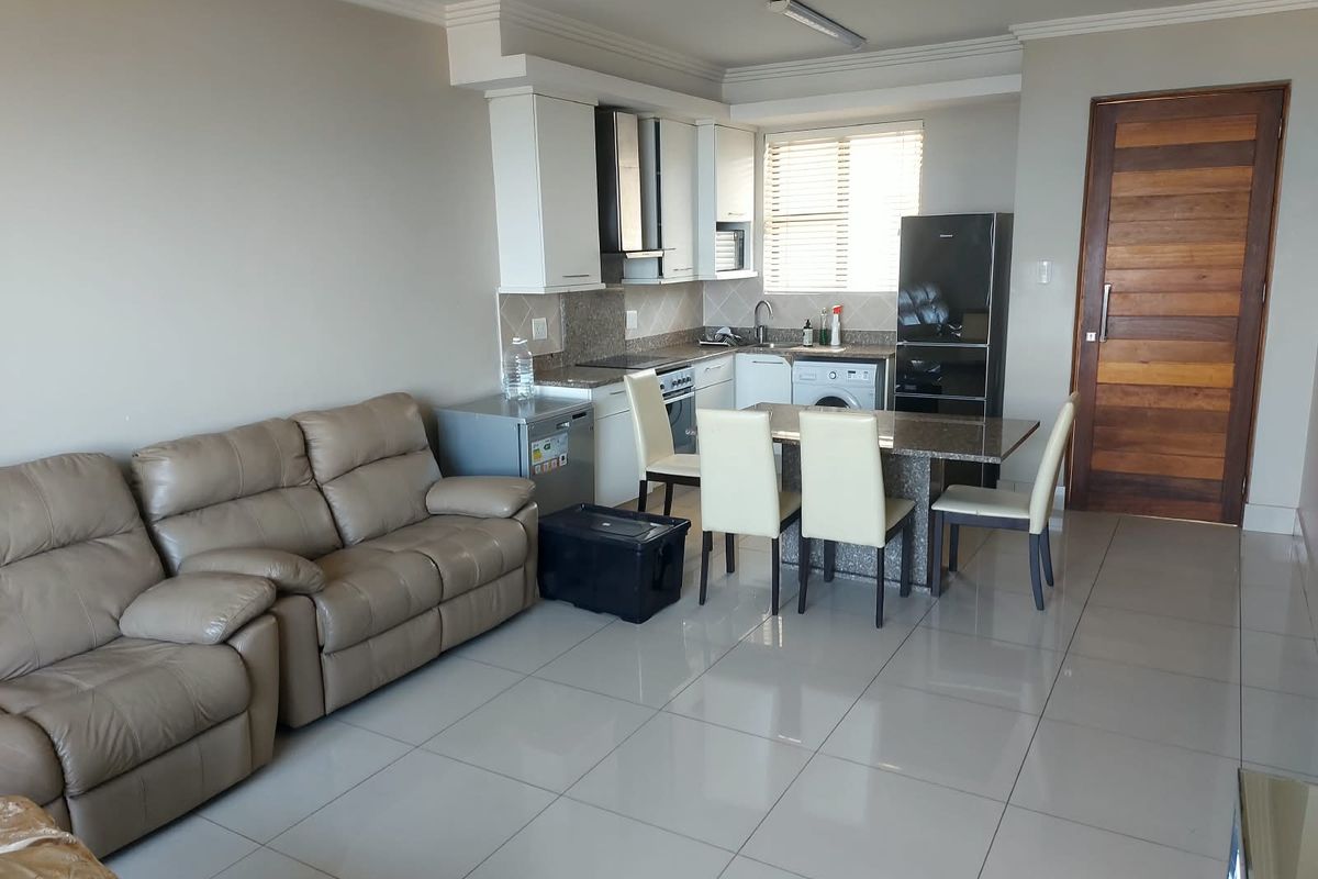 Open-plan living and kitchen area featuring tiled floors, modern cabinetry with granite countertops, and a functional layout suitable for contemporary apartment living.