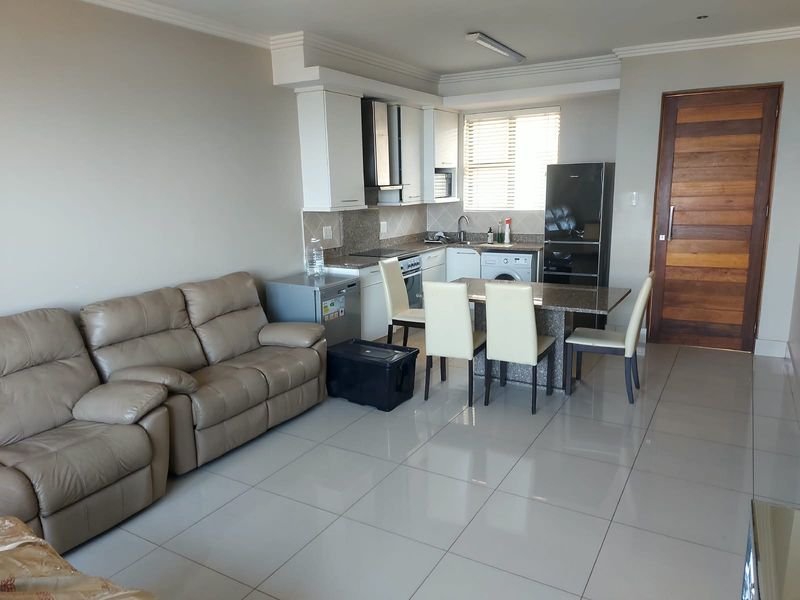 Open-plan living and kitchen area featuring tiled floors, modern cabinetry with granite countertops, and a functional layout suitable for contemporary apartment living.