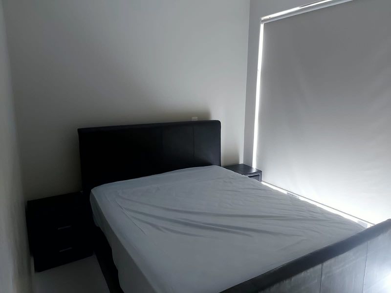 A simple bedroom featuring neutral walls and a functional roller blind for light control.