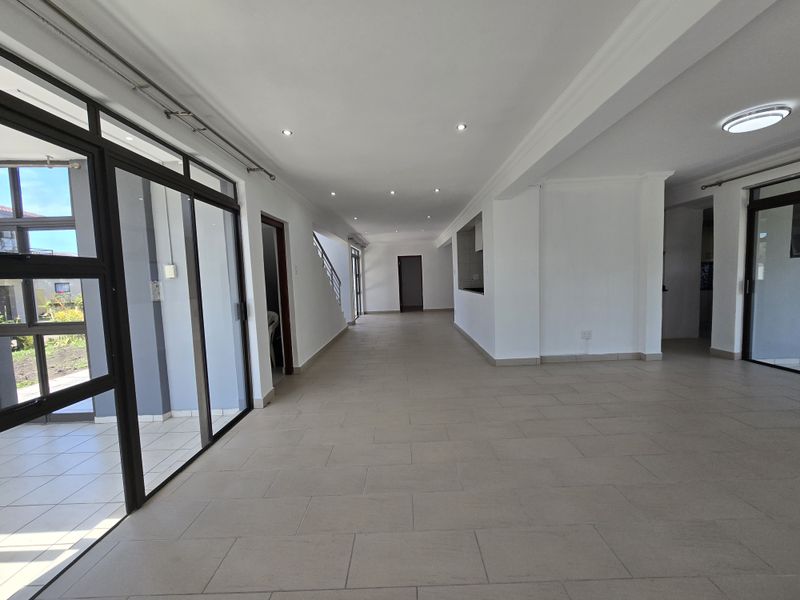 Spacious open-plan living area featuring neutral tiled flooring, recessed lighting, and large sliding glass doors providing ample natural light and access to the exterior.