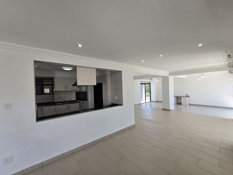Spacious open-plan living area featuring a functional kitchen with built-in cabinetry, tiled floors, and seamless flow to the dining and lounge spaces.