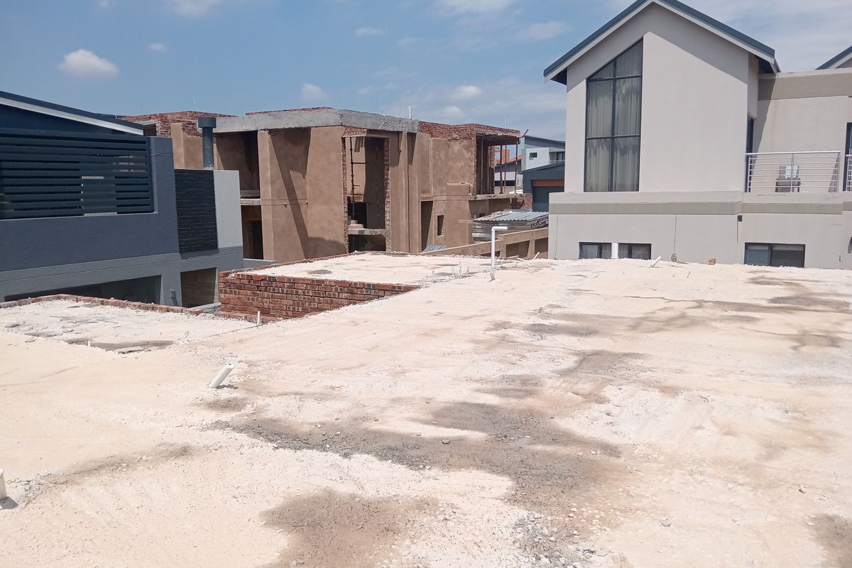 An elevated view of an unfinished concrete slab roof area under construction, showing surrounding residential development.
