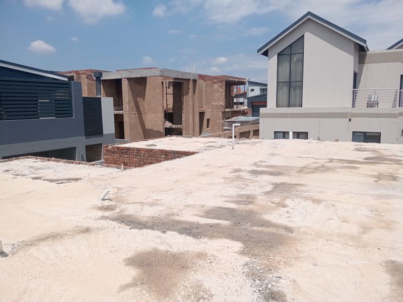 An elevated view of an unfinished concrete slab roof area under construction, showing surrounding residential development.