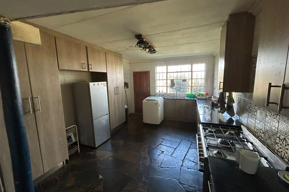 A functional kitchen featuring built-in cabinetry, a gas hob, double sink, and distinctive stone tile flooring with a tiled backsplash.