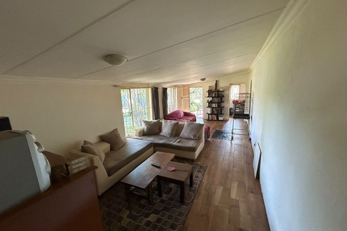A spacious living area featuring wood-look tile flooring and large sliding glass doors that provide natural light and access to the exterior.
