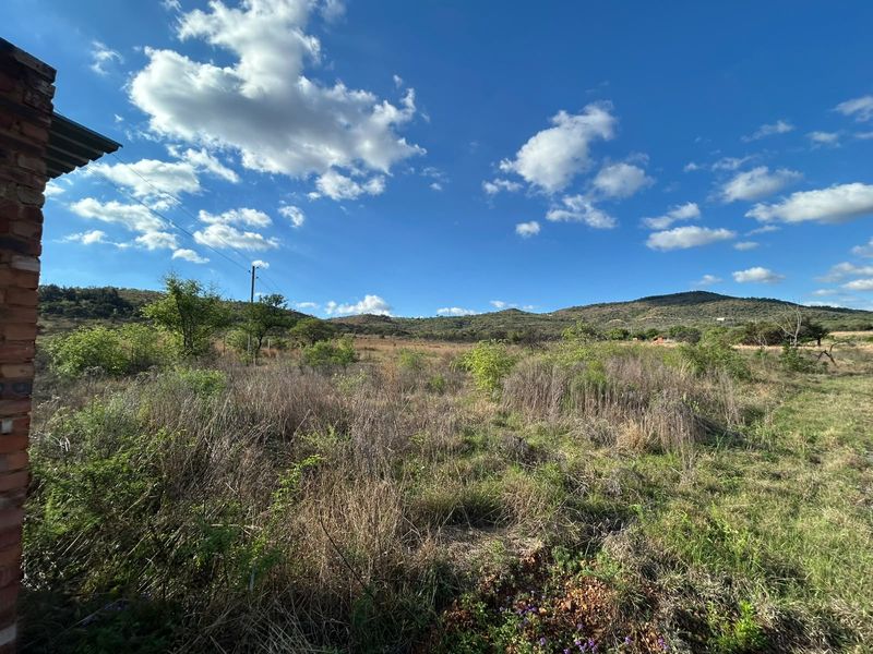 A wide-angle view of the expansive rural landscape and rolling hills surrounding the property, featuring natural vegetation and clear blue skies.