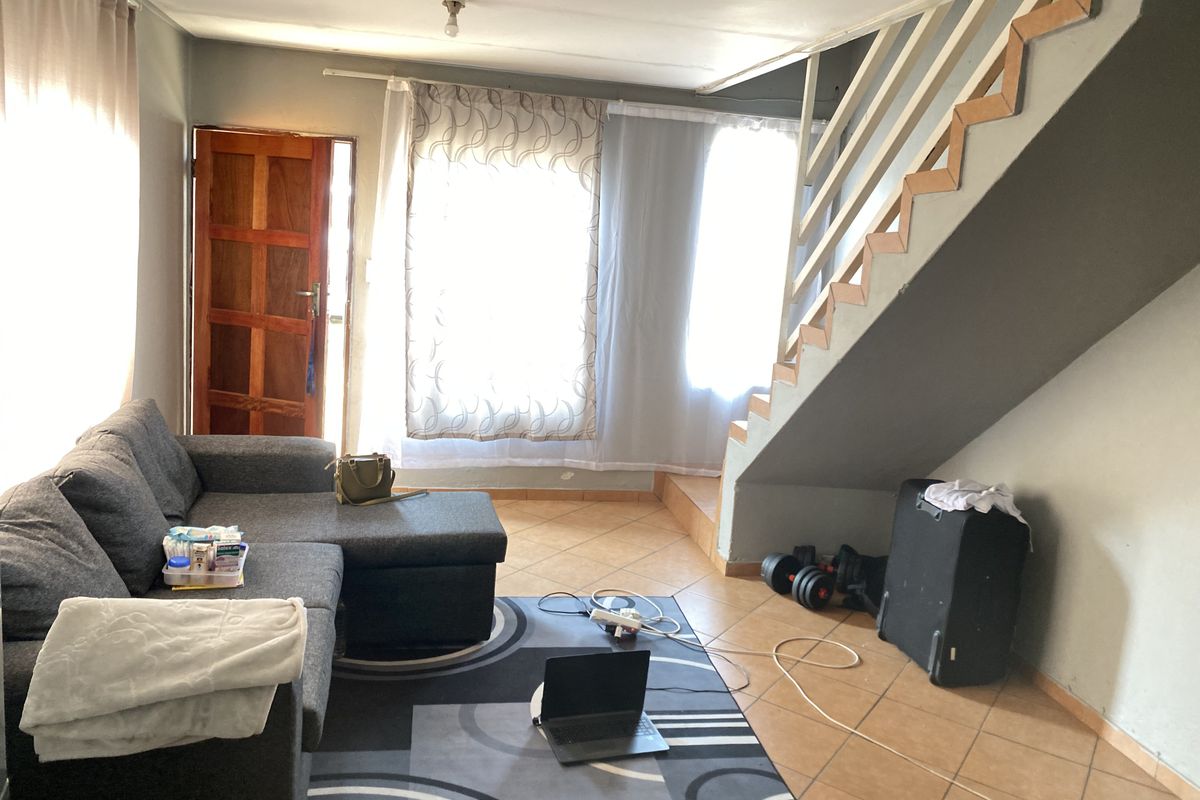 A living room area featuring tiled flooring and an internal staircase, providing access to the upper level of the home.