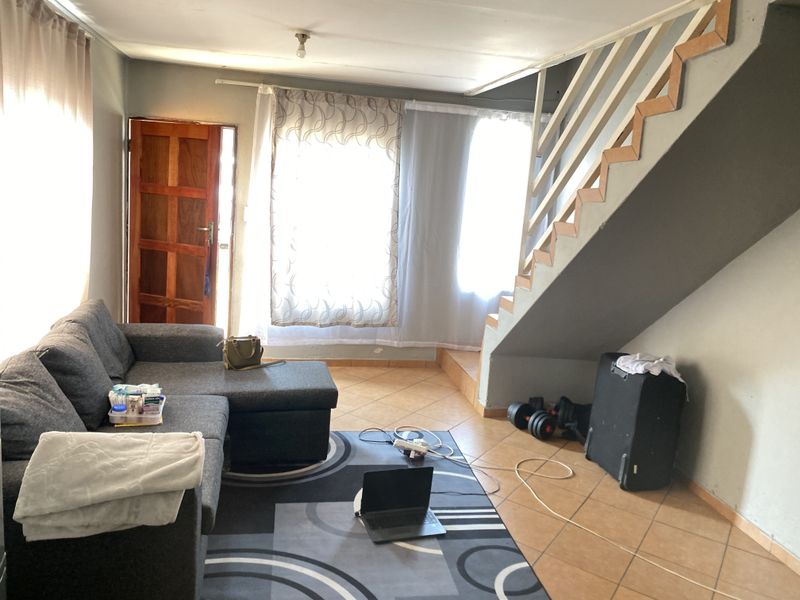 A living room area featuring tiled flooring and an internal staircase, providing access to the upper level of the home.