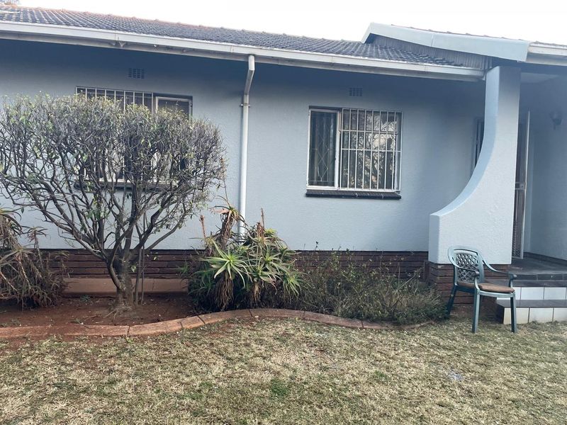 Front facade of the house featuring a tiled roof, security bars on windows, and a brick plinth base with an adjacent garden area.