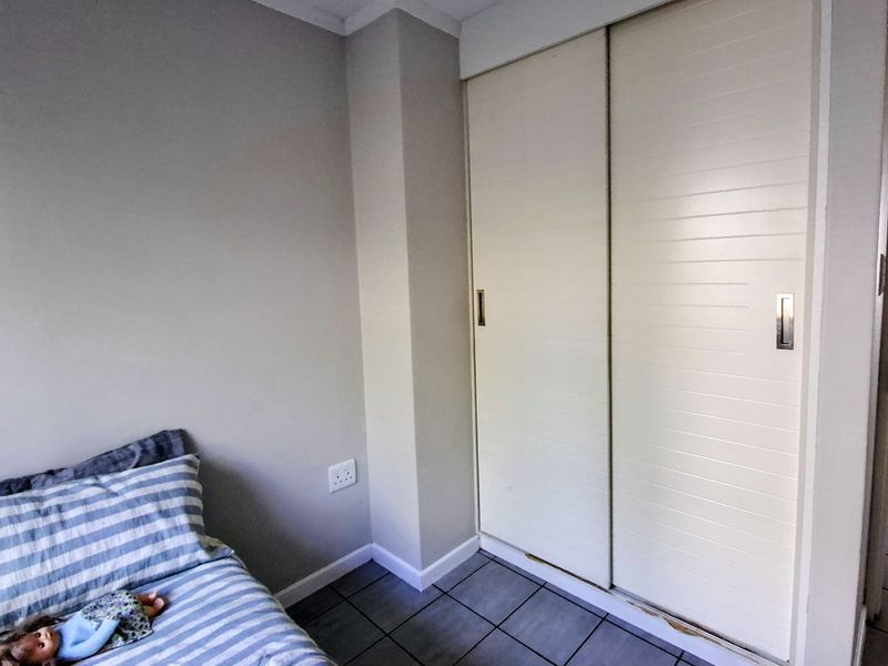A bedroom featuring tiled flooring and a built-in sliding door wardrobe with some visible wear to the lower trim.