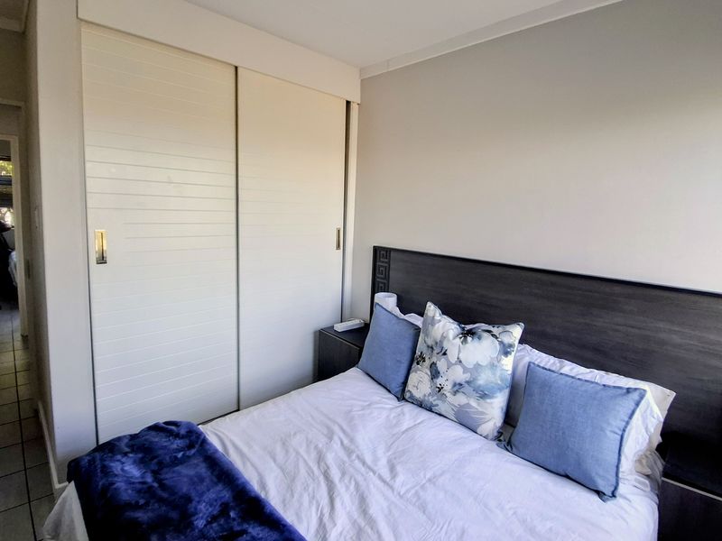 A well-maintained bedroom featuring a built-in sliding door wardrobe and neutral wall finishes.