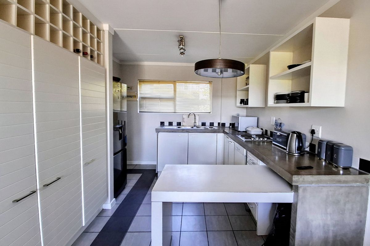 Modern kitchen featuring concrete countertops, ample built-in cabinetry with integrated wine storage, tiled flooring, and functional open shelving.
