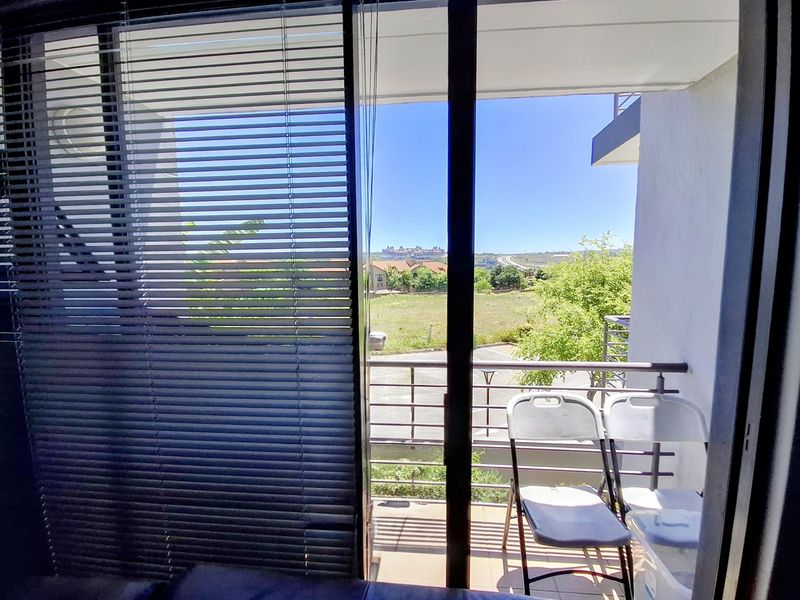 A balcony featuring tiled flooring and a metal balustrade, offering an open view of the surrounding landscape.