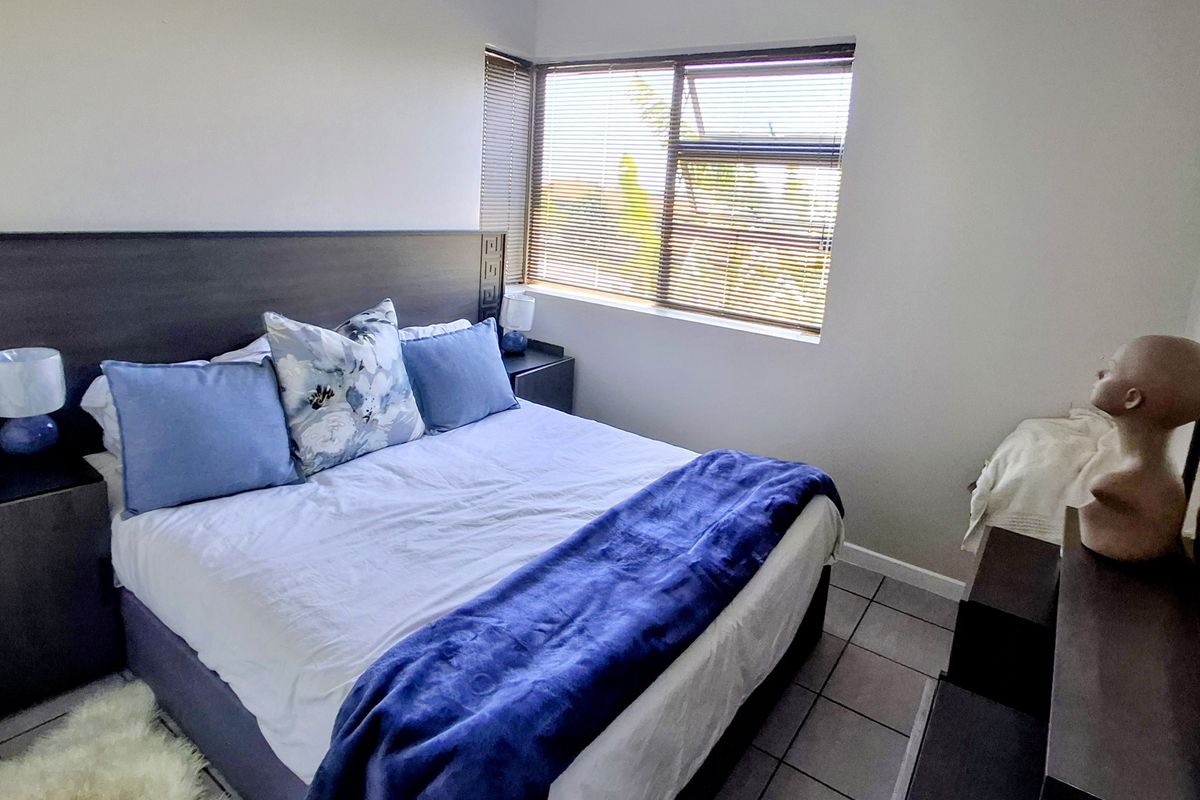 A functional bedroom featuring tiled flooring and fitted venetian blinds, offering a neutral space ready for personalization.
