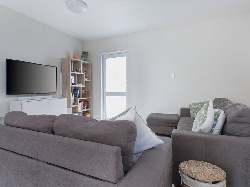 A bright and neutral living room featuring a glass panel door providing natural light and access to the exterior.