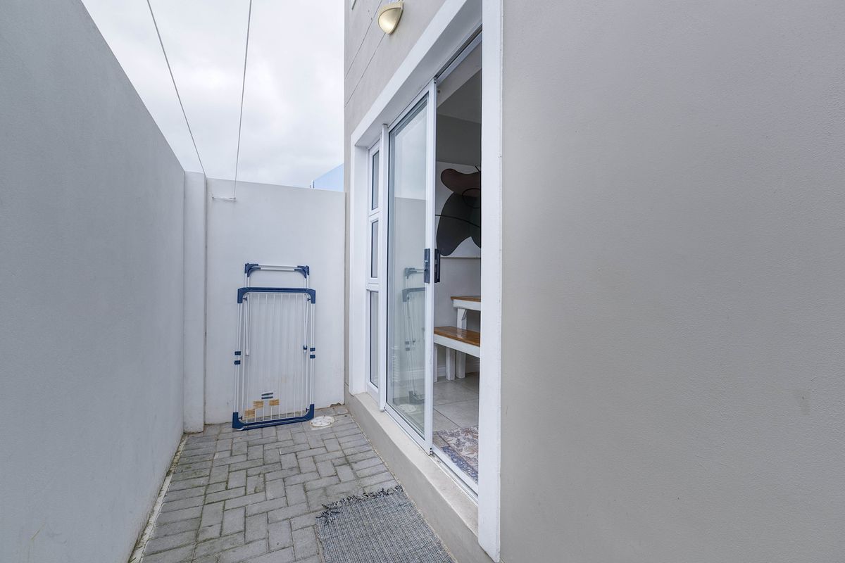 A compact rear courtyard featuring paved flooring, a sliding glass door entrance, and a secure boundary wall.