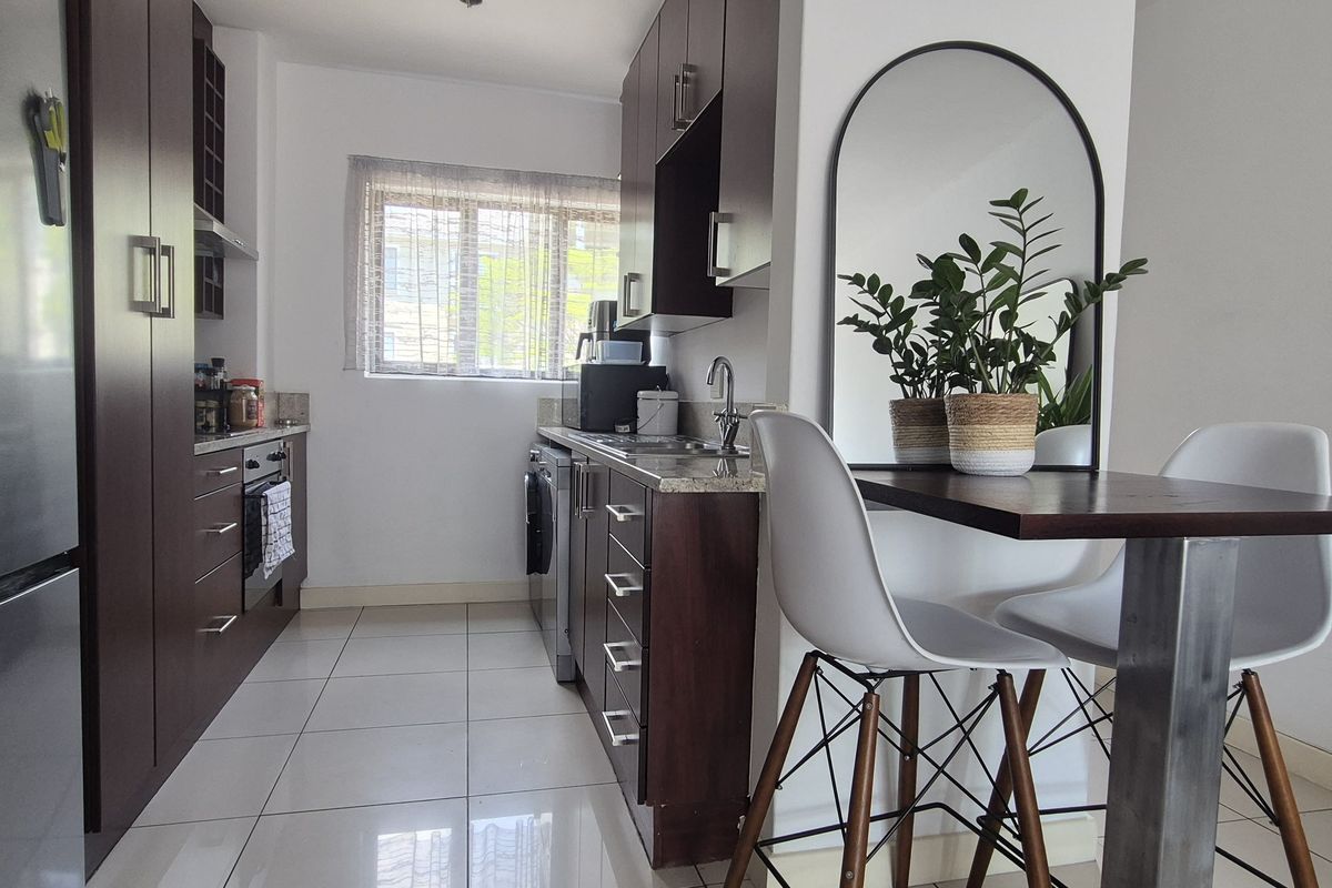 A compact, modern kitchen featuring dark wood cabinetry, granite countertops, and sleek ceramic floor tiles, providing a functional and well-maintained cooking space.