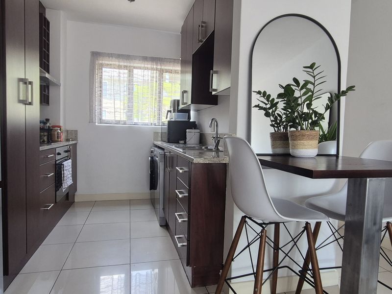 A compact, modern kitchen featuring dark wood cabinetry, granite countertops, and sleek ceramic floor tiles, providing a functional and well-maintained cooking space.