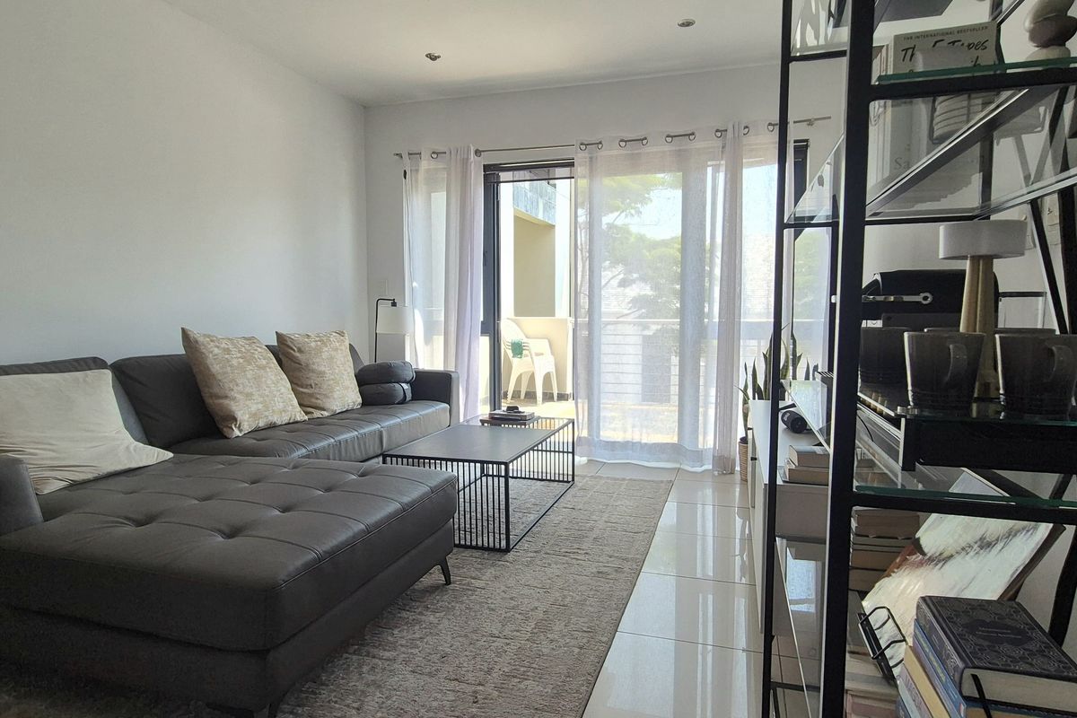 A bright living room featuring tiled flooring and a large sliding glass door providing access to an outdoor balcony area.